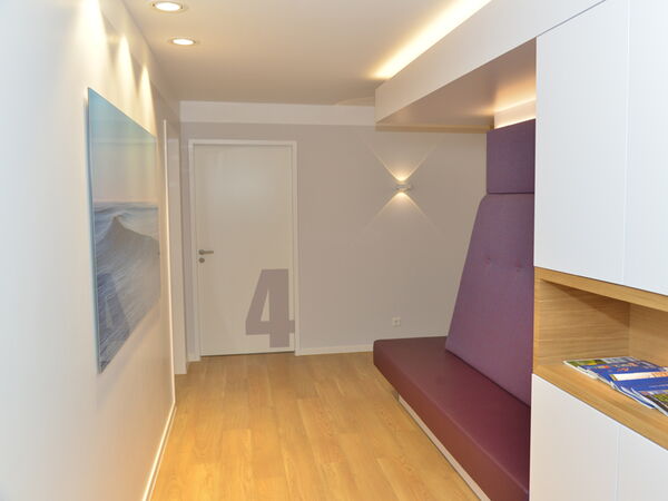 Heller, freundlicher Flur mit klaren Linien und modernen Designelementen, Blickrichtung Wartebereich vor den Praxisräumen.