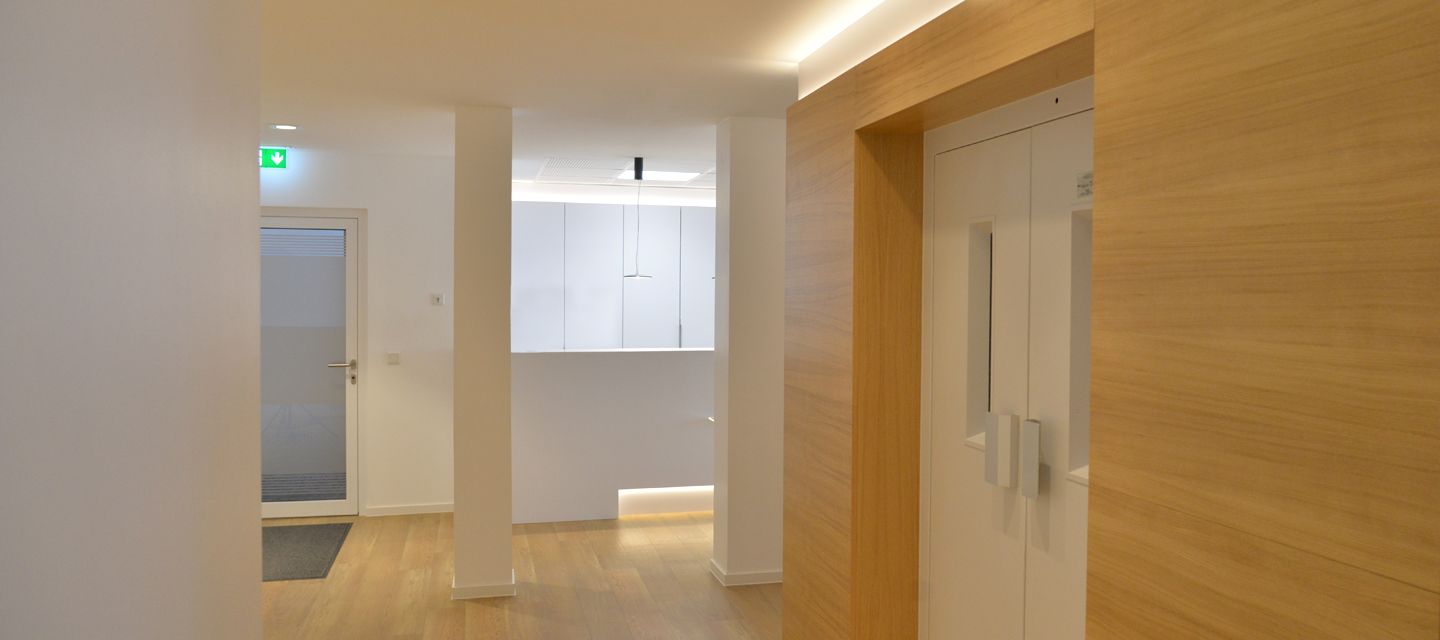 Heller, freundlicher Flur mit klaren Linien und modernen Designelementen, Blickrichtung Eingang der Praxis.